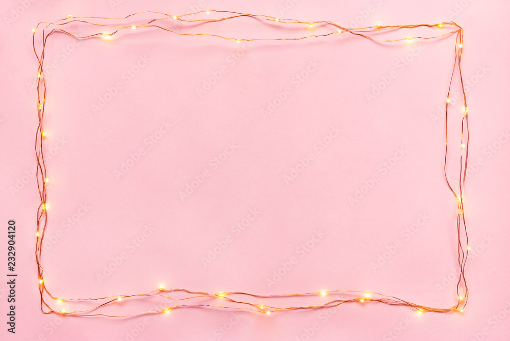 Christmas lights garland border over pink background. Flat lay, copy space.