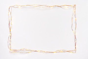 Christmas lights garland border over white background. Flat lay, copy space.