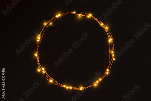 Obraz na płótnie Christmas lights garland circular border over black background. Flat lay, copy space. w salonie