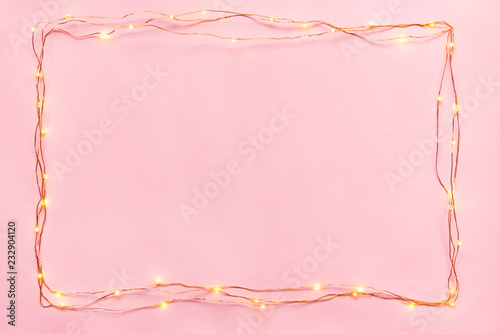 Obraz na płótnie Christmas lights garland border over pink background. Flat lay, copy space. w salonie