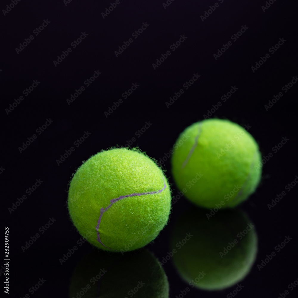 Yellow tennis ball with reflection below  on black background