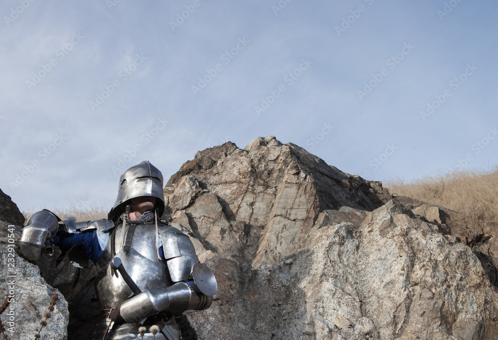Knight with a sword and in medieval armor on the background of granite stone Knight with a sword and in medieval armor on the background of granite stone
