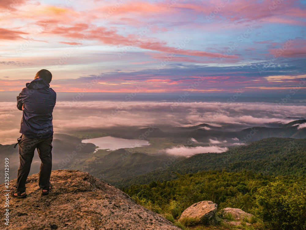 Traveler stand on Rocky cilff with sunsire sky and beautiful cloud sea on 