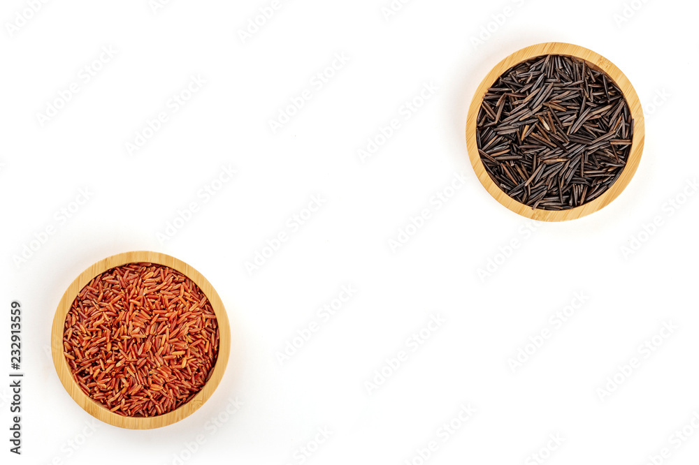 Red rice and black wild rice, shot from the top in wooden bowls on a white background, forming a frame with a place for text Red rice and black wild rice, shot from the top in wooden bowls on a white background, forming a frame with a place for text
