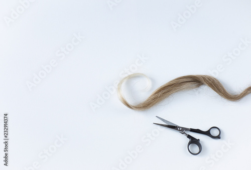 curl of blond hair and scissors - background on hairdressing services