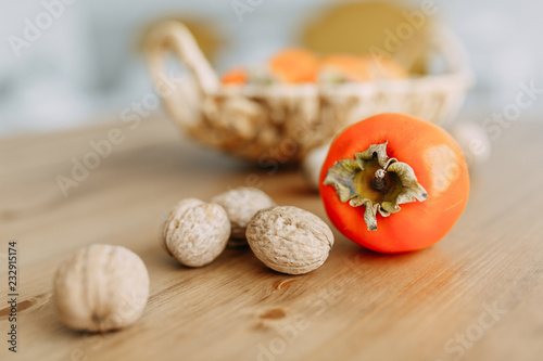 Persimmon fruits and walnuts in a wicker basket. Agriculture and harvesting concept