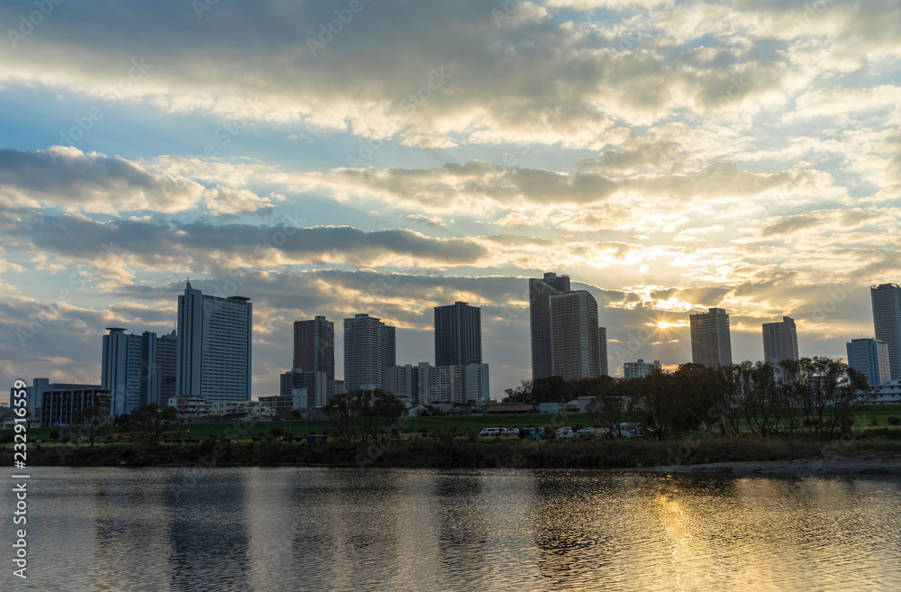 the sun sets in the buildings across the Tama River Kawasaki Kanagawa Japan