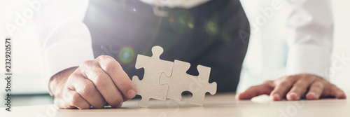 Cuadro en lienzo Wide view image of a businessman holding two puzzle pieces matched together
