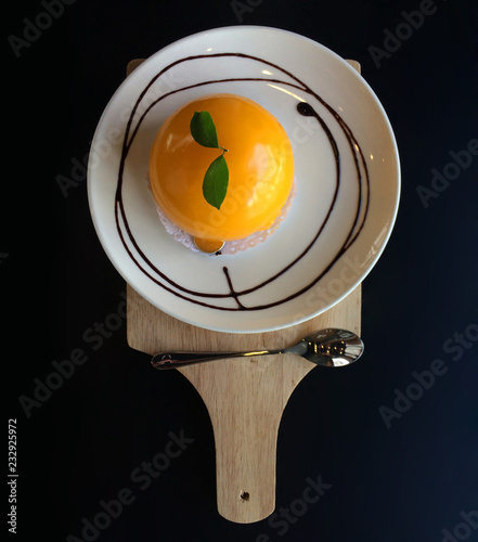 Orange cake on white plate on black background