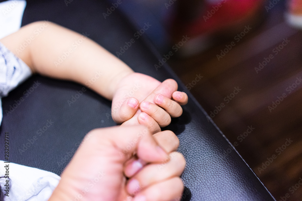 A boy is holding his parent finger to show his trust and believe.