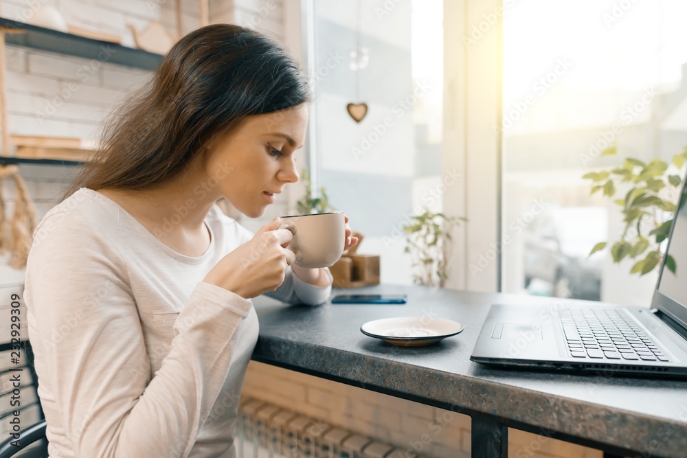 Young female blogger in coffee shop with laptop computer and cup of fresh coffee Young female blogger in coffee shop with laptop computer and cup of fresh coffee