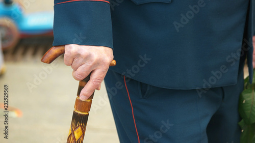 Old military man with a walking cane. Close up hand of an elderly War veteran using walking stick outdoors. Day of Victory. photo