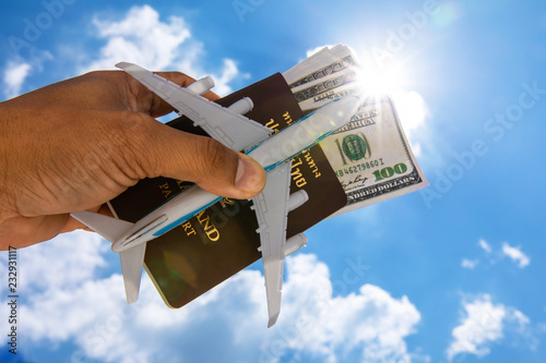 thailand passport - travelling by air - dollar money with aircraft modell in the dand against blue sky photo