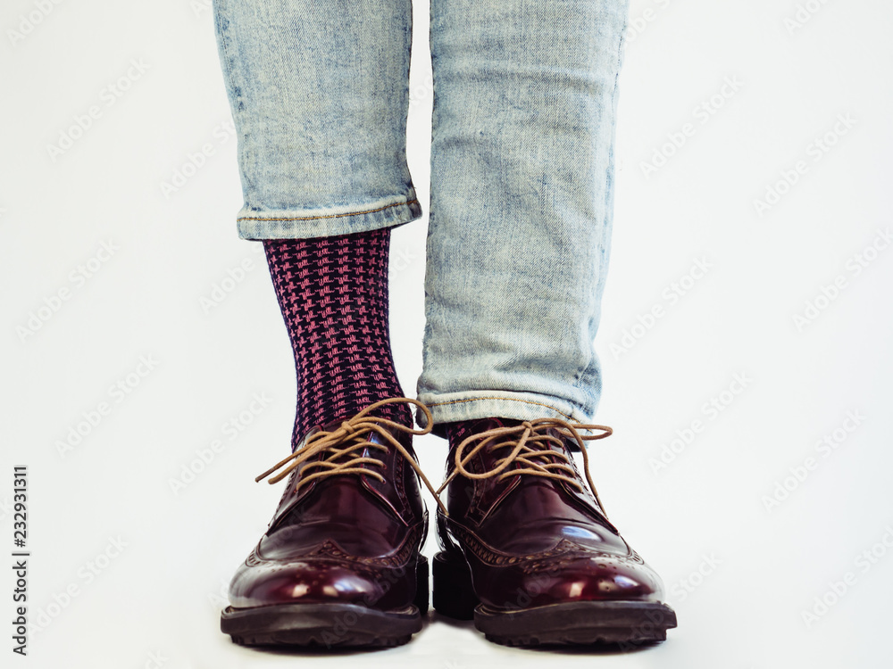 Men's legs in stylish, vintage shoes and bright, multi-colored socks. White background, isolated, close-up. Сoncept of fashion and elegance