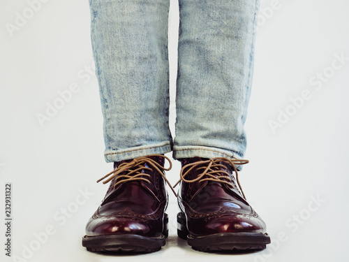 Men's legs in stylish, vintage shoes and bright, multi-colored socks. White background, isolated, close-up. Сoncept of fashion and elegance