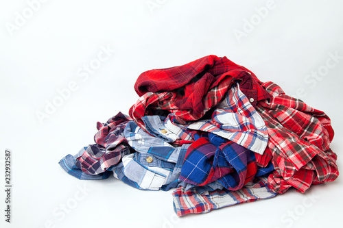 pile of men's colored clothes plaid shirts on a white background
