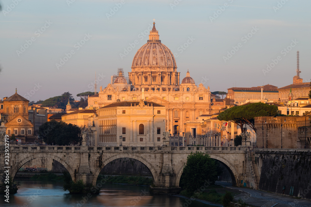 St. Peter's Cathedral in Rome, Italy, and the Tiber River against blue sky at sunrise