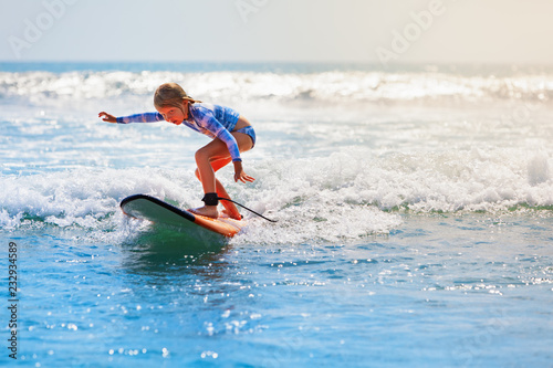 Photography Happy baby girl - young surfer ride on surfboard with fun on sea waves