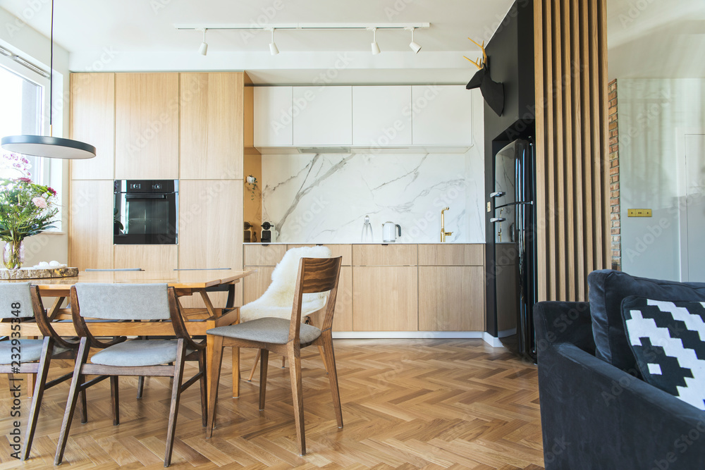 Stylish and modern open space with dining and living room with sofa and family table. Bright and sunny room with plants and brown wooden parquet. Bright and sunny interior Stylish and modern open space with dining and living room with sofa and family table. Bright and sunny room with plants and brown wooden parquet. Bright and sunny interior