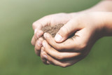 close up on the hands of a child who takes care of his land