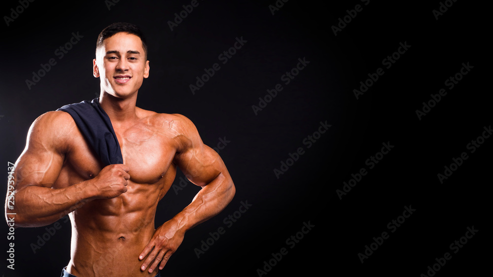 Smiling athletic male with towel on dark background Smiling athletic male with towel on dark background