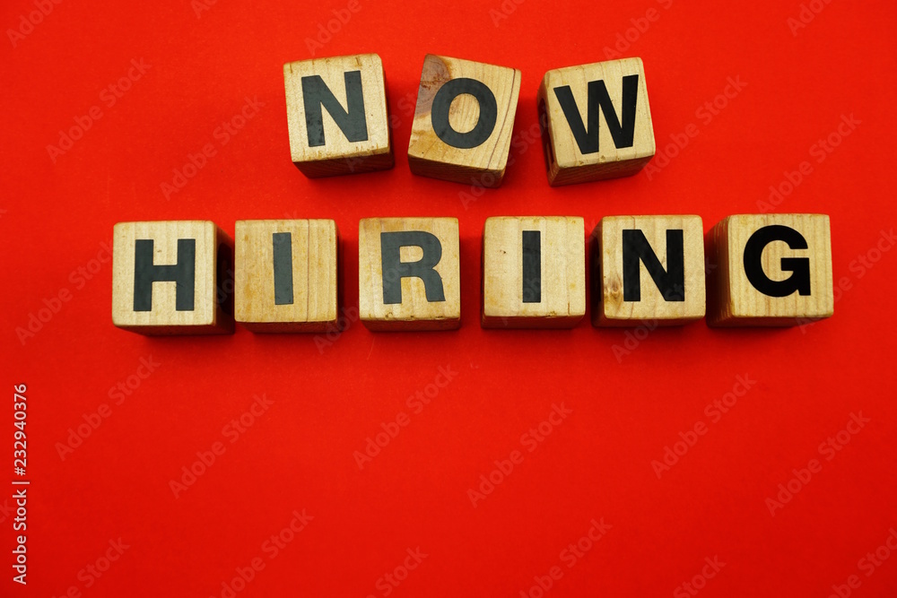 Obraz premium Now Hiring word created with cubes alphabet letters on red background