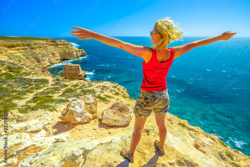 Freedom young woman at Island Rock, a natural limestone in Australian Coral Coast, Kalbarri National Park. Scenic panorama of turquoise Indian Ocean. Sunny with blue sky. Western Australia Outback. Freedom young woman at Island Rock, a natural limestone in Australian Coral Coast, Kalbarri National Park. Scenic panorama of turquoise Indian Ocean. Sunny with blue sky. Western Australia Outback.