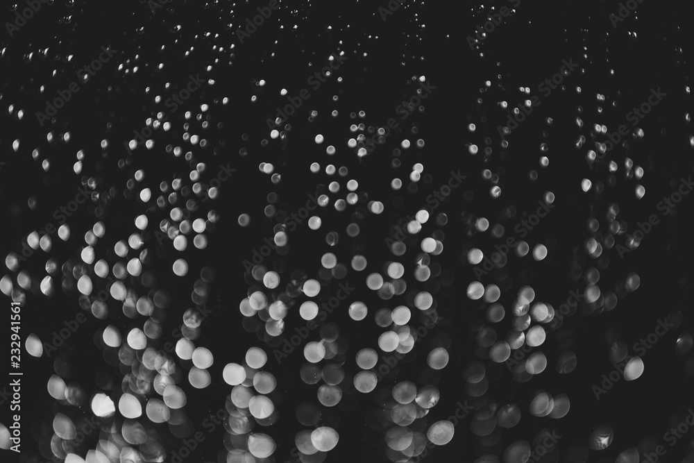 bokeh of lights made by raindrops on a windows illuminated by a torch, abstract background or texture shot