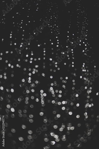 bokeh of lights made by raindrops on a windows illuminated by a torch  abstract background or texture shot