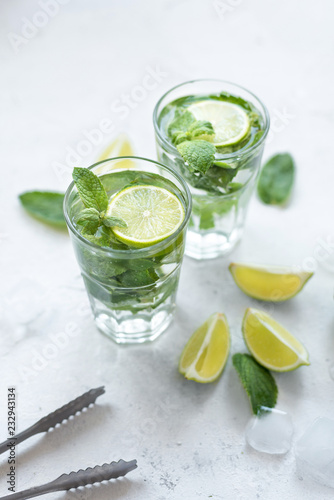 Summer refreshing cocktail mojito with lime and mint on white background.Slices of lime, mint, glass with ice cubes on white background.