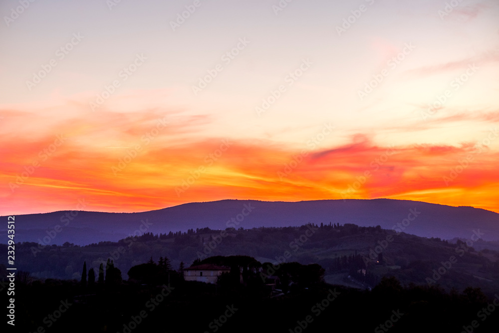 Amazing coloured sunset in Tuscany Italy with red clouds and blue ground during the blue hours. Beautiful landscape with colors and feeling