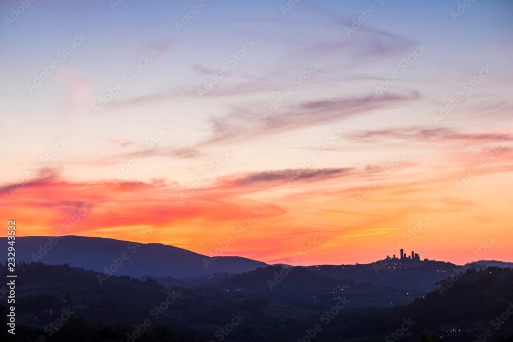 San Gimignano Tuscany view after a great coloured sunset in the beautiful wine valley in Italy. Colors red and blue and ancient town tower in silhouette
