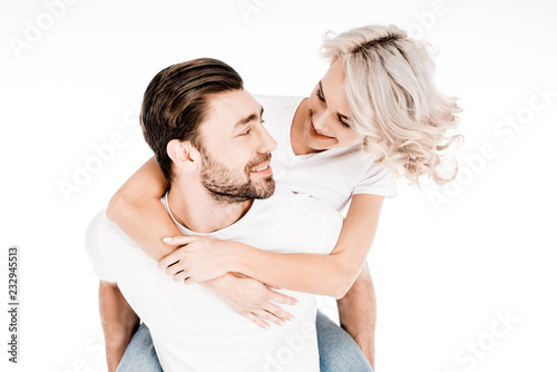 Handsome young adult man giving piggyback to wonderful blonde woman isolated on white