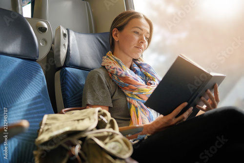 Relaxed young woman reading on the train photo