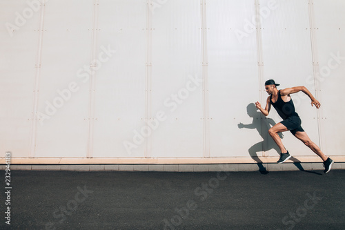 Fotografija Young man runner running along wall with copy space