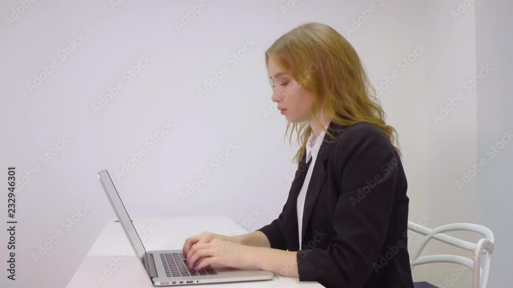Beautiful female office worker typing on laptop keyboard in office Beautiful female office worker typing on laptop keyboard in office