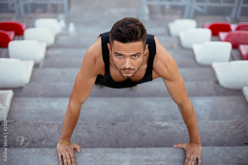 Serious man doing pushups on stadium stairs Serious man doing pushups on stadium stairs