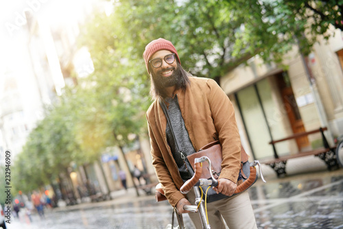 Hipster guy standing with bicycle in the street