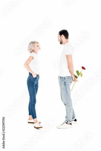 Beautiful couple looking at eahc other while man holding flower behind the back isolated on white photo