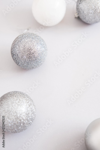 White Christmas background. Glossy silver and glitter decoration balls. Minimalist style. Copyspace for text  overhead