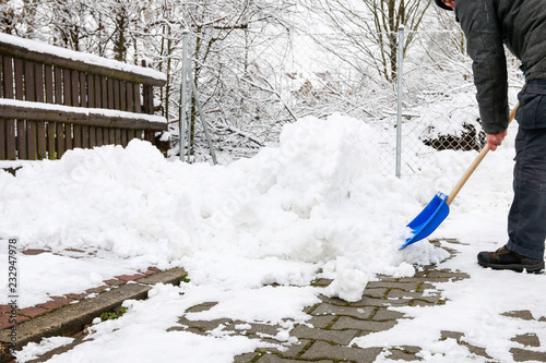 Man removing snow from the sidewalk after snowstorm.