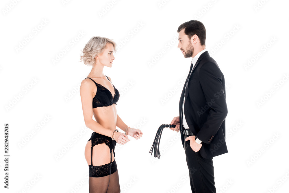 Handsome man holding whip while woman standing in lingerie and handcuffs  isolated on white Photos | Adobe Stock