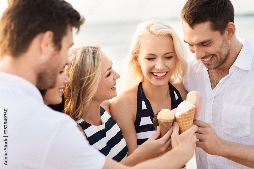 friendship, leisure and people concept - group of happy friends in striped clothes eating ice cream on beach friendship, leisure and people concept - group of happy friends in striped clothes eating ice cream on beach
