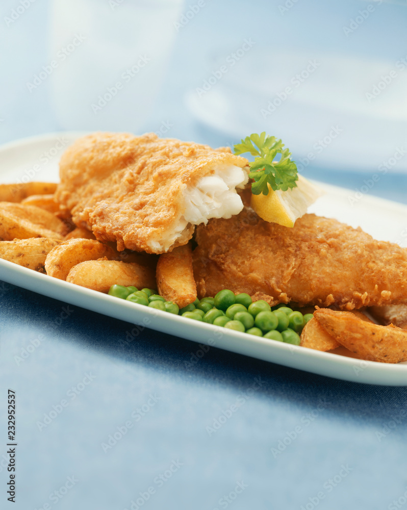 Crispy battered deep fried cod and chips with peas, close-up.