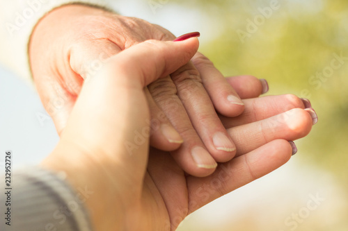 Senior and young hands, bokeh background