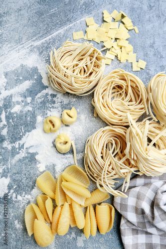 Mixed types and shapes of italian pasta on grey stone, background