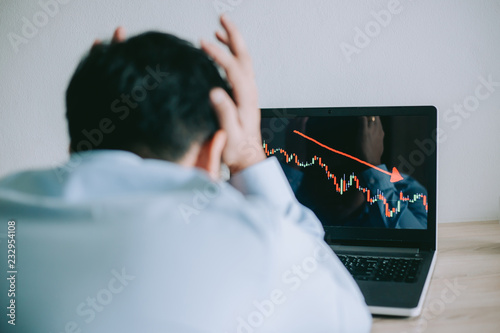 Stress Business man look at to the laptop show financial market chart graphic going down. Stock market concept.