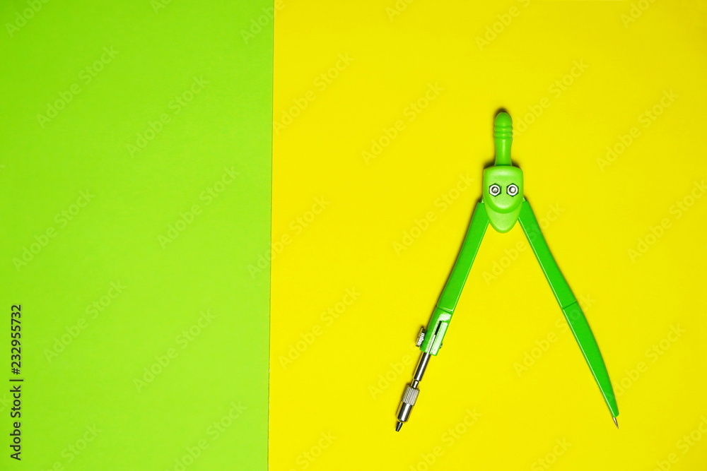 green compasses for circle drawing in design school education on contrast yellow background green compasses for circle drawing in design school education on contrast yellow background