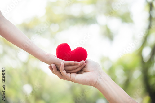 Hand giving red heart to hand. Love   health care   health insurrance concept.