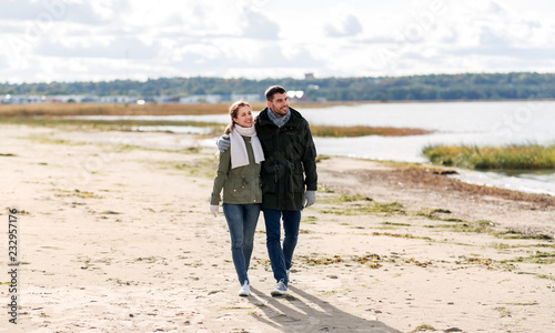 love, relationship and people concept - smiling couple walking along autumn beach and holding hands